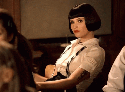 A Woman With A Tattoo On Her Arm Is Wearing A White Shirt And Black Tie GIF