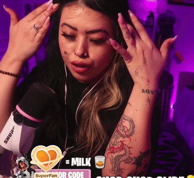a woman with a tattoo on her arm stands in front of a microphone and a sign that says milk