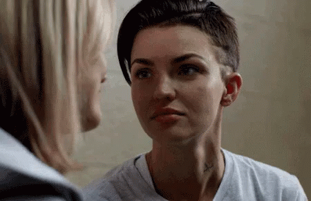 A Woman With A Tattoo On Her Neck Is Looking At Another Woman . GIF