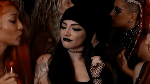 A Woman With A Tattoo On Her Shoulder Is Smiling In A Crowd Of People GIF