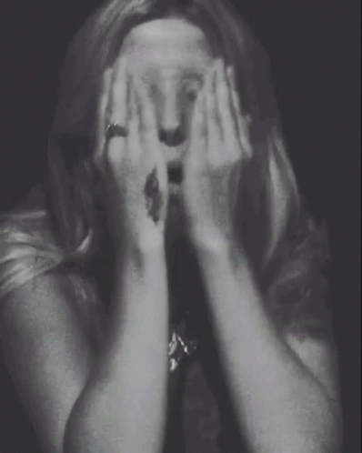 A Woman With A Tattoo On Her Wrist Covering Her Face GIF