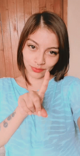 A Woman With A Tattoo On Her Wrist Giving A Peace Sign GIF