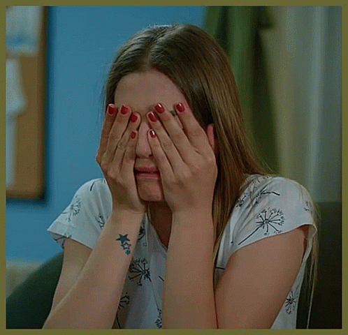 A Woman With A Tattoo On Her Wrist Is Covering Her Face GIF