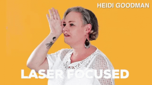 A Woman With A Tattoo On Her Wrist Is Wearing A White Shirt And Earrings And Says Laser Focused GIF