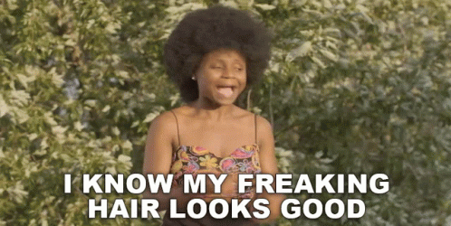 A Woman With An Afro Is Standing In Front Of A Tree And Says I Know My Freaking Hair Looks Good . GIF