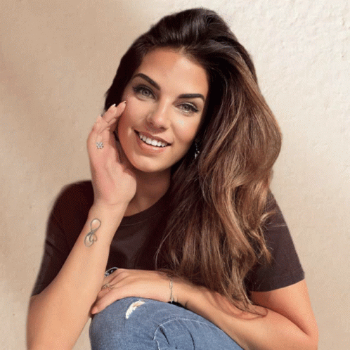 A Woman With An Infinity Tattoo On Her Wrist Smiles GIF