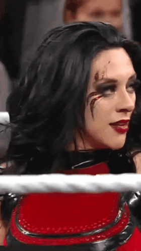 A Woman With Black Hair And Red Lipstick Is Standing In A Ring . GIF