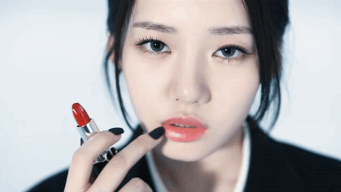 A Woman With Black Nail Polish Is Applying Red Lipstick To Her Lips GIF