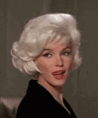 a woman with blonde hair and a black jacket is making a face .