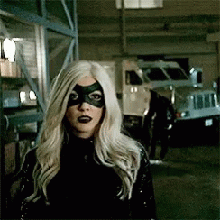 A Woman With Blonde Hair And A Black Mask Is Standing In Front Of A Truck . GIF