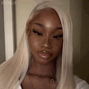 A Woman With Blonde Hair And A Nose Ring Is Wearing A White Shirt And A Heart Necklace . GIF