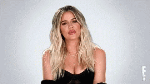 A Woman With Blonde Hair And A Plunging Neckline Is Wearing A Black Dress . GIF