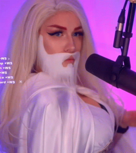 A Woman With Blonde Hair And A White Beard Is Standing In Front Of A Microphone GIF
