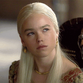 A Woman With Blonde Hair And Gold Earrings Looks To The Side GIF