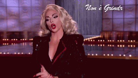 A Woman With Blonde Hair And Red Lips Is On A Stage With The Words Non E Grindr Below Her GIF
