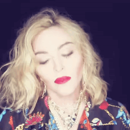 A Woman With Blonde Hair And Red Lips Is Wearing A Floral Shirt GIF