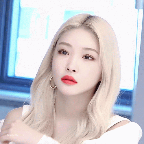 A Woman With Blonde Hair And Red Lips Is Wearing Hoop Earrings And A White Top GIF