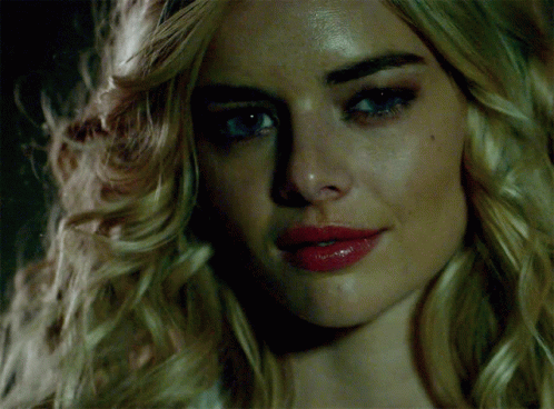A Woman With Blonde Hair And Red Lips Looks At The Camera GIF