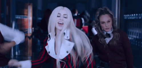 A Woman With Blonde Hair Is Dancing In A Crowded Room While Two Other Women Look On . GIF