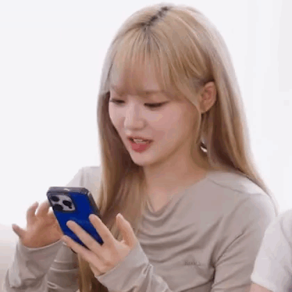 A Woman With Blonde Hair Is Holding A Cell Phone In Her Hand . GIF