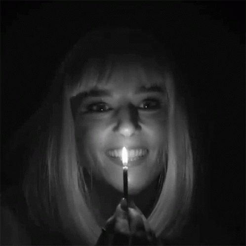 a woman with blonde hair is holding a lit match in her mouth ..
