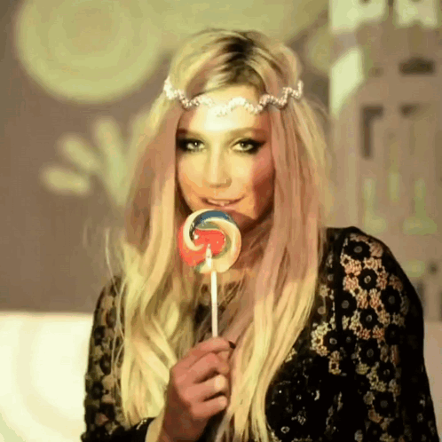 A Woman With Blonde Hair Is Holding A Lollipop In Her Hand GIF