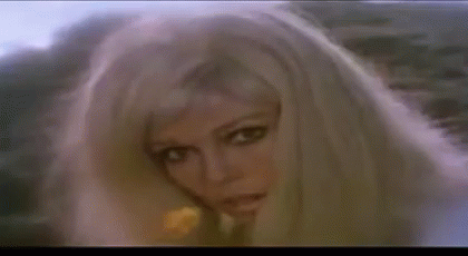 A Woman With Blonde Hair Is Holding A Yellow Flower In Her Hand . GIF