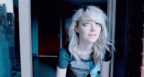A Woman With Blonde Hair Is Looking Out Of A Window GIF