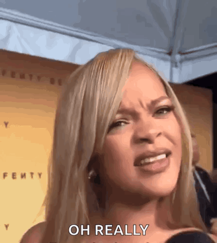 A Woman With Blonde Hair Is Making A Funny Face While Talking Into A Microphone . GIF