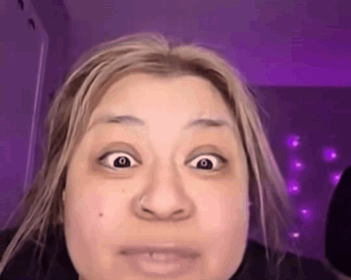 a woman with blonde hair is making a funny face with her eyes wide open .