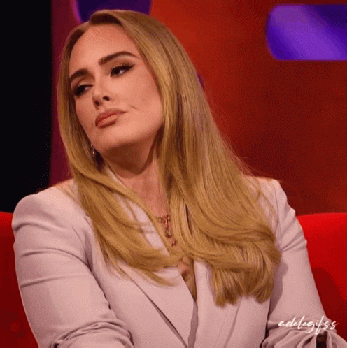 A Woman With Blonde Hair Is Sitting On A Red Couch With The Words Edelagifs Written On The Bottom GIF