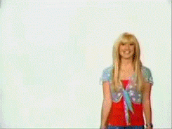 A Woman With Blonde Hair Is Smiling In Front Of A White Wall GIF
