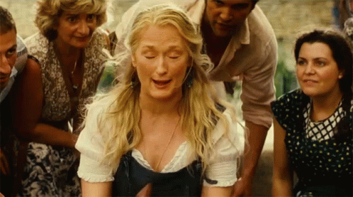 A Woman With Blonde Hair Is Surrounded By A Group Of People GIF