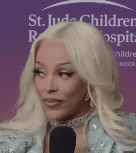 A Woman With Blonde Hair Is Talking Into A Microphone In Front Of A St. Jude Children 'S Hospital Sign GIF