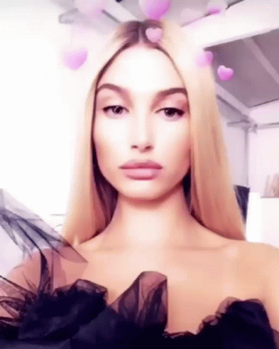 A Woman With Blonde Hair Is Wearing A Black Dress And Taking A Selfie . GIF