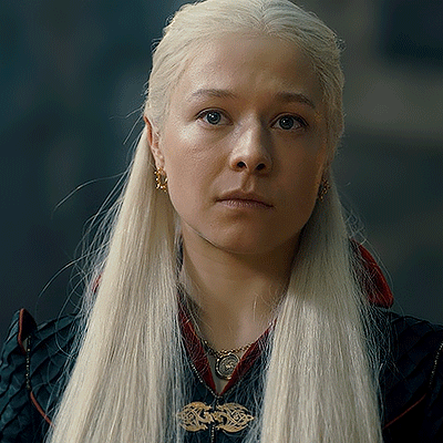 A Woman With Blonde Hair Is Wearing A Black Jacket And A Necklace GIF
