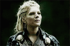 A Woman With Blonde Hair Is Wearing A Black Jacket And Earrings And Looking Up . GIF