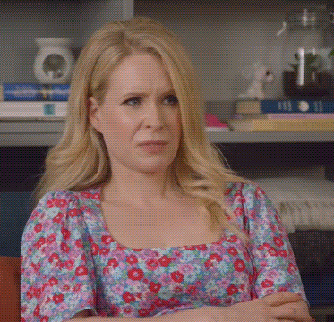 A Woman With Blonde Hair Is Wearing A Floral Dress GIF