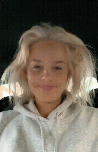 A Woman With Blonde Hair Is Wearing A Gray Hoodie GIF