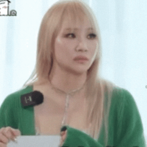 A Woman With Blonde Hair Is Wearing A Green Sweater And Holding A Microphone In Her Hand . GIF