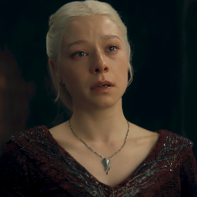 A Woman With Blonde Hair Is Wearing A Necklace With A Pendant GIF