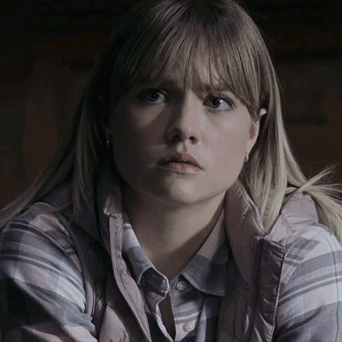 A Woman With Blonde Hair Is Wearing A Plaid Shirt And A Grey Vest GIF