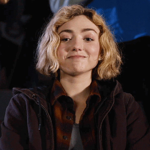 A Woman With Blonde Hair Wearing A Brown Jacket GIF