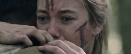 A Woman With Blood On Her Face Is Holding A Man 'S Arm GIF