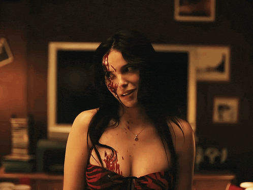 A Woman With Blood On Her Face Is Standing In Front Of A Tv GIF