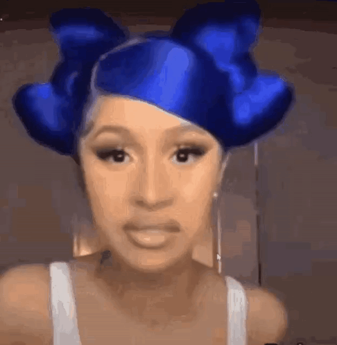 A Woman With Blue Hair And A Blue Bow In Her Hair Is Making A Funny Face . GIF