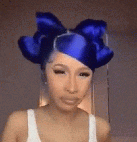A Woman With Blue Hair And A Blue Bow In Her Hair Is Making A Funny Face . GIF