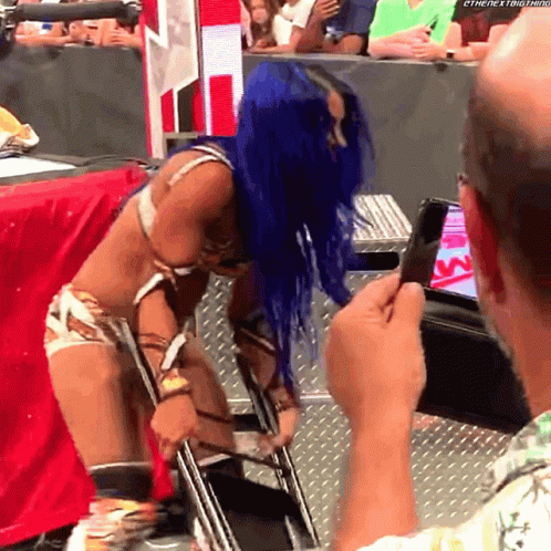 A Woman With Blue Hair Is Being Photographed By A Man With A Cell Phone GIF