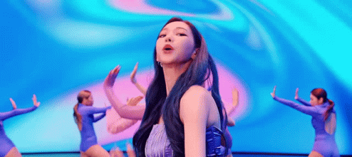a woman with blue hair is dancing on a stage in front of a crowd .