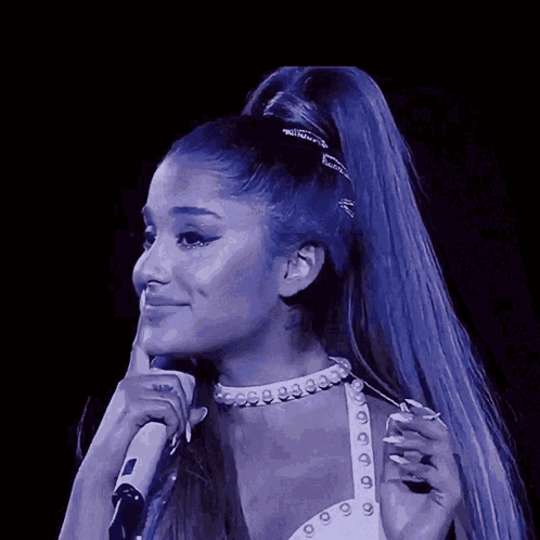A Woman With Blue Hair Is Holding A Microphone And Smiling GIF